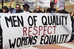 Mensen met een spandoek met de tekst "MEN OF QUALITY RESPECT WOMENS EQUALITY"