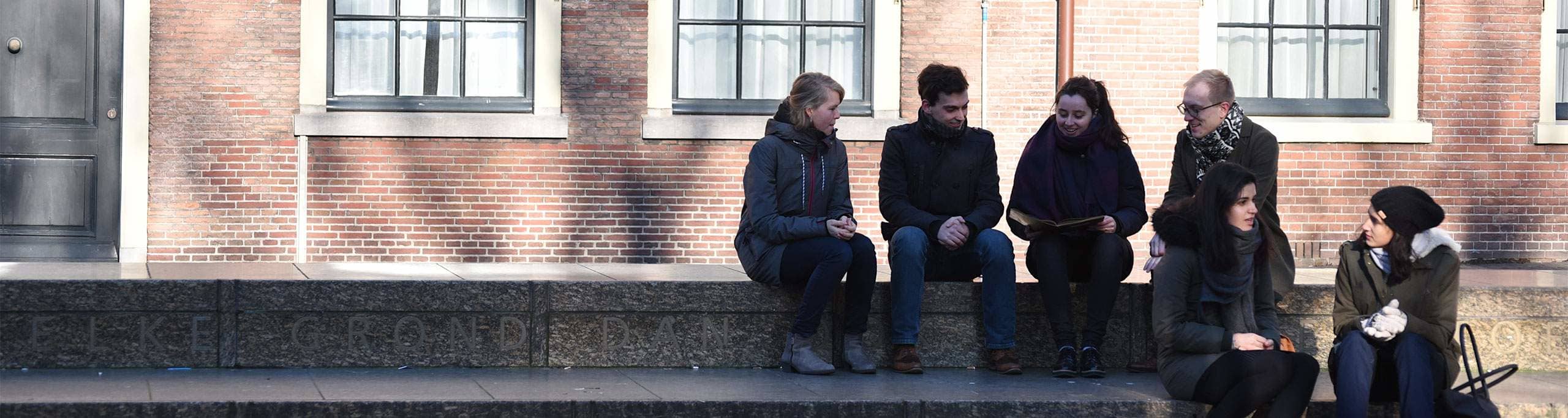 Jongeren zitten op de 45 meter lange Grondwetbank te Den Haag